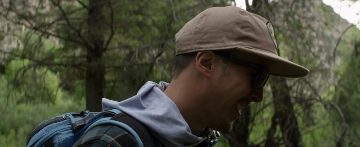 A man smiles as he hikes through a wooded area