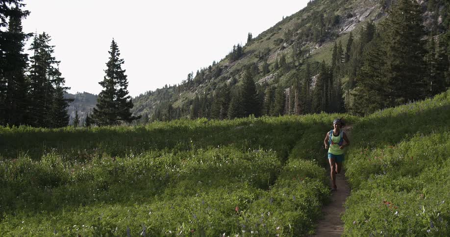 A woman jogs on a dirt trail in the mountains