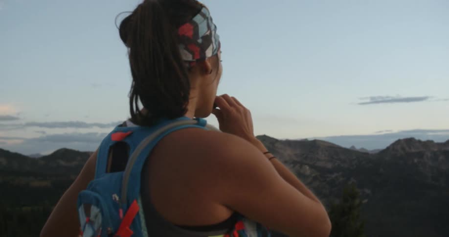 A woman drinks water and looks out at some mountains