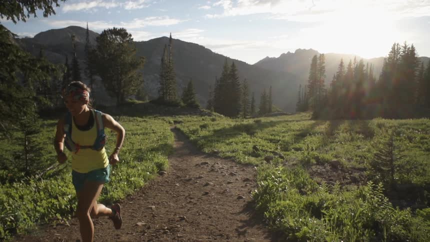 Woman jogs on a dirt trail in the forest