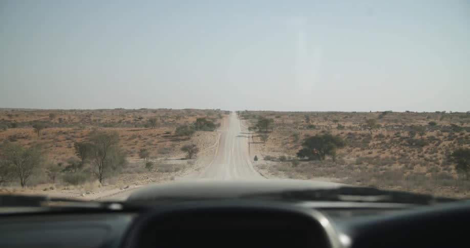 A car travels across a desert landscape on a dirt road