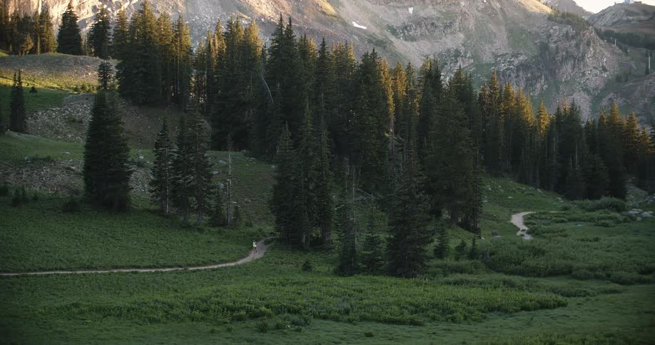 A person runs on a path near a forest mountainside