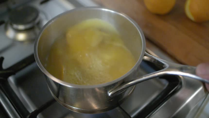 A hand agitating a pot of soup over a stove