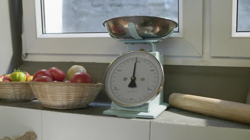 A windowsill with a scale fresh vegetables and other items