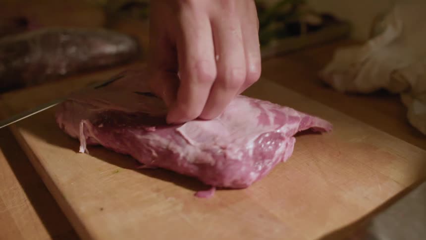 A person cutting the fat off of a piece of meat