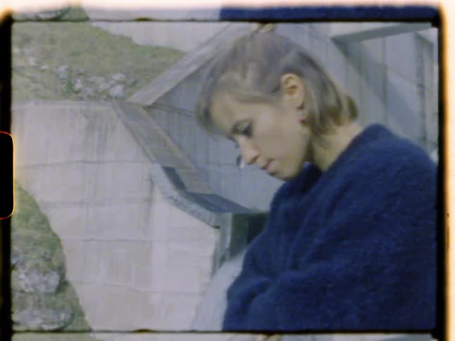 A man sitting on a wall overlooking a woman standing in front of a building