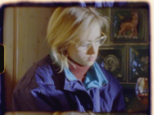 A woman drinks wine at a table with a photograph in hand