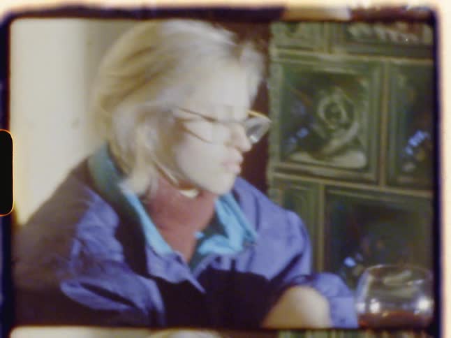 Blonde woman sitting at the table holds a glass of wine during daylight
