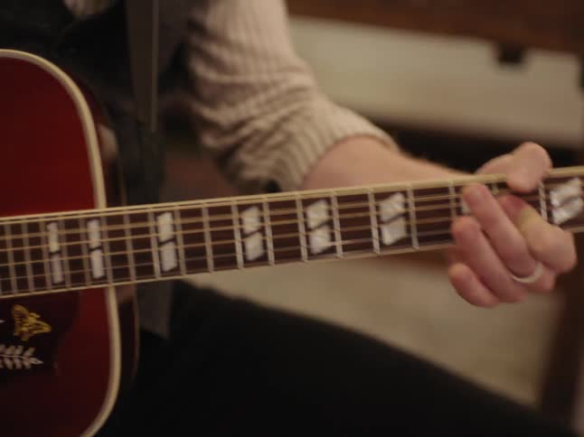 A man plays an acoustic guitar with flowers painted on it