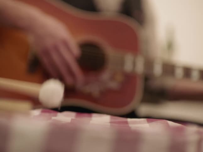 A person plays on the drums beside a person playing the guitar