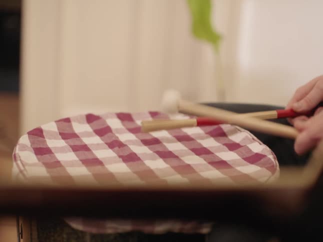 A person is drumming on a cloth covered drum