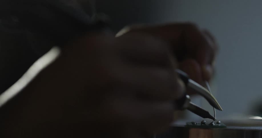 A person solders a wire in a dark room
