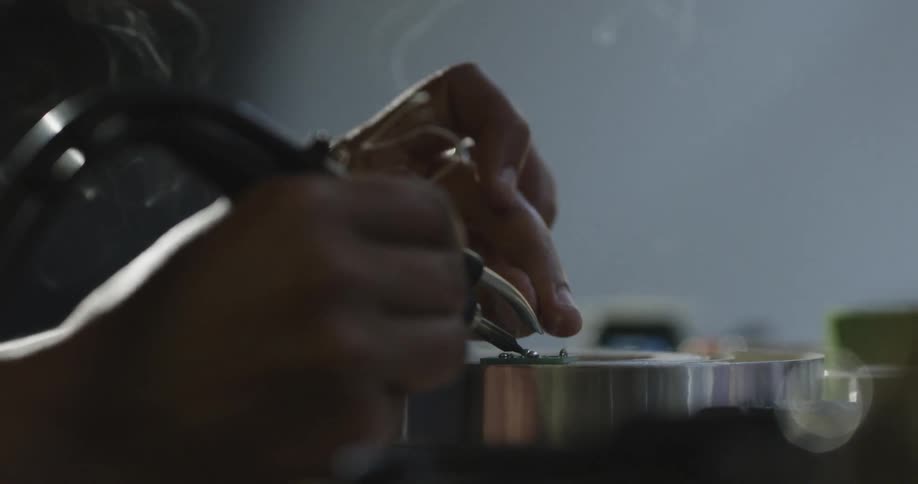 A person using a soldering iron on metal