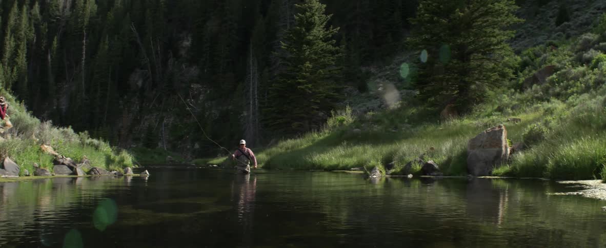Man stands in a river fly fishing