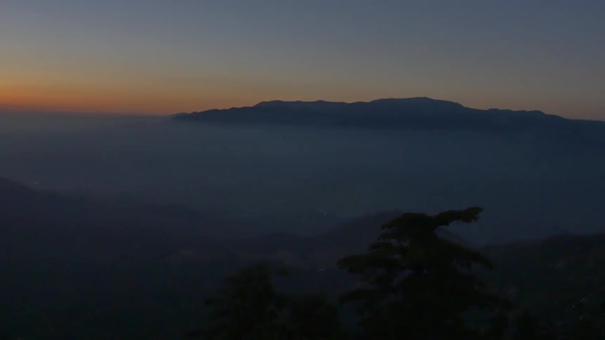 An aerial view of a mountain and surrounding terrain at dusk