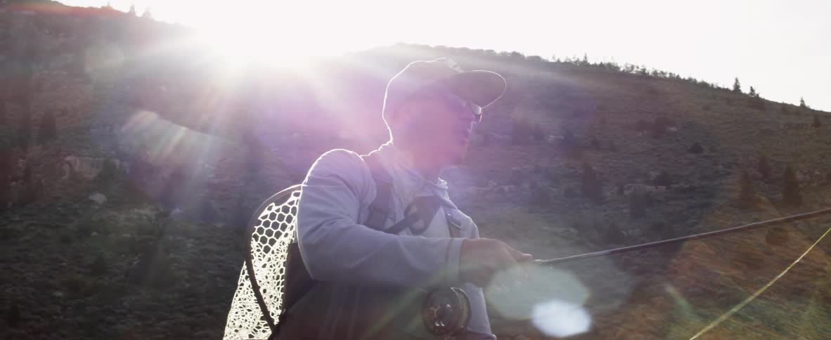 A man is fly fishing on a sunny day