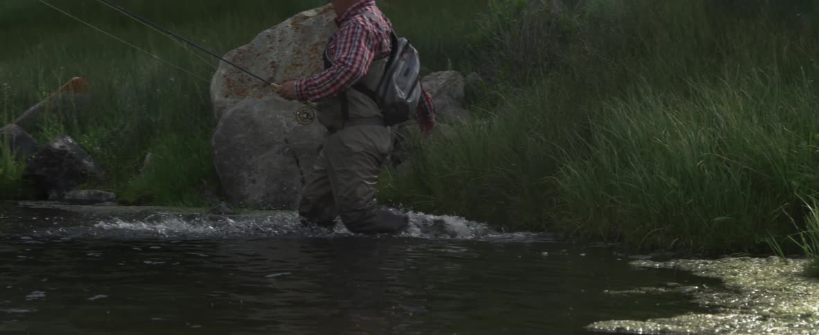 A man walks into the water with a fishing pole