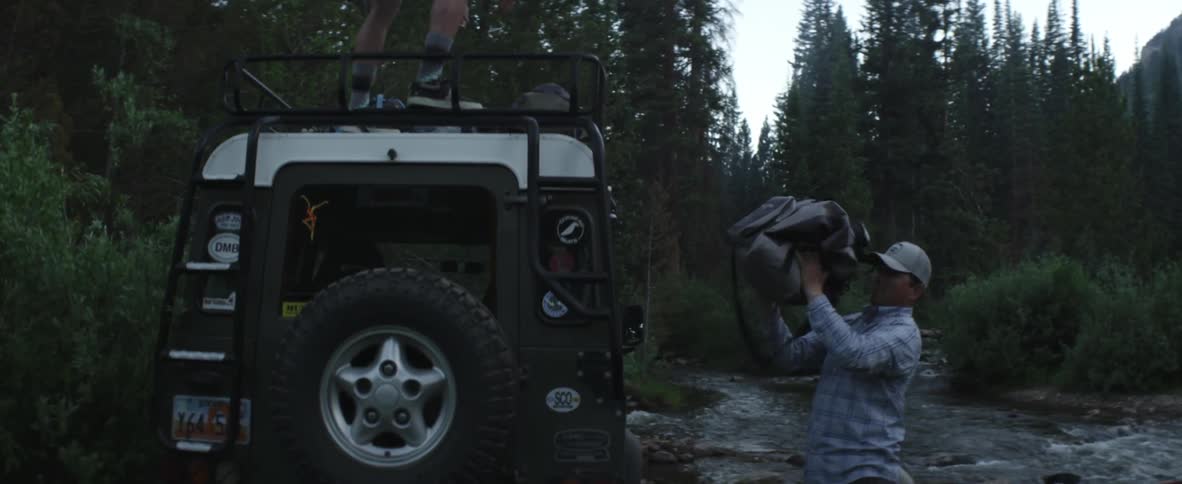 Two men gather hiking gear in the woods