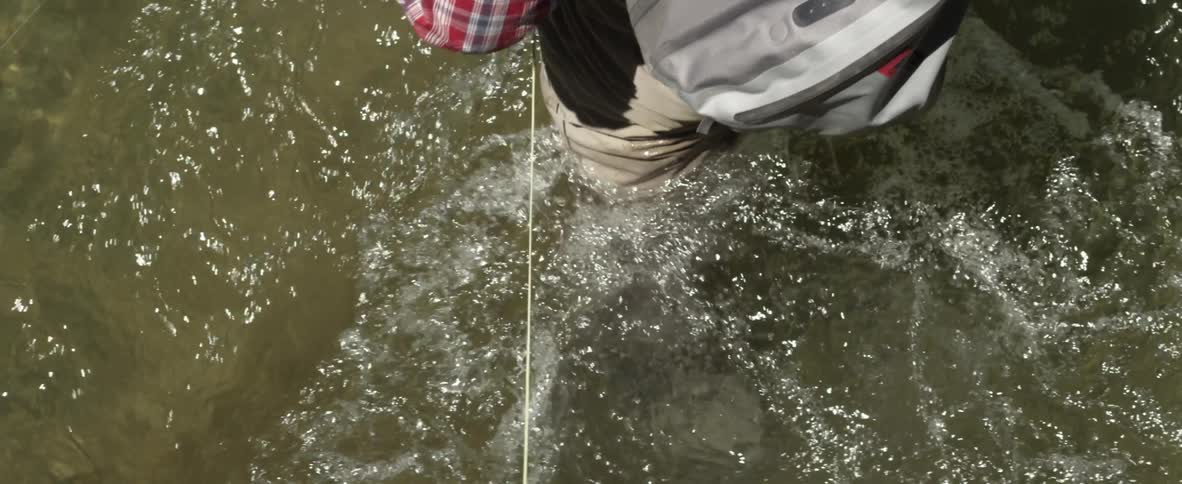 A man's fishing line floats behind him