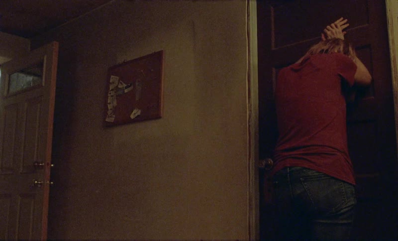 An upset woman banging on a closed wooden door