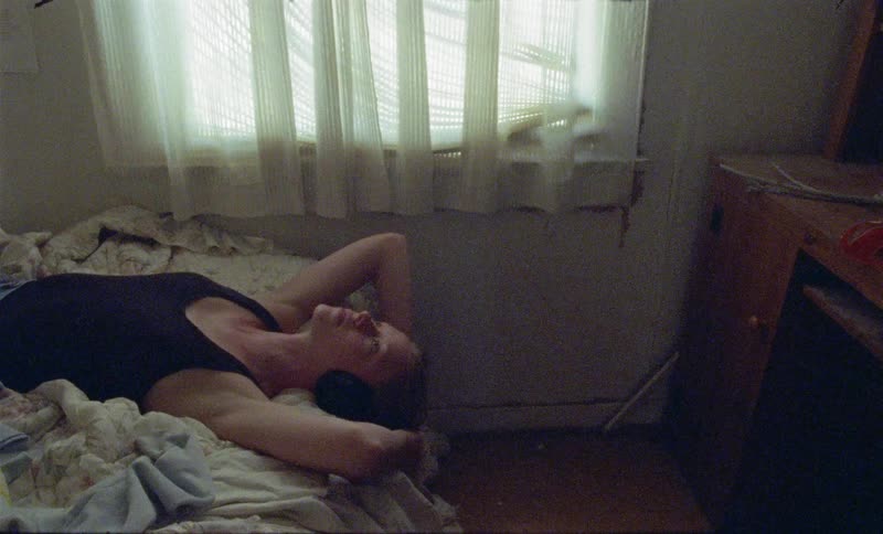 A woman laying in bed with headphones staring at the ceiling