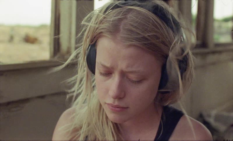 A woman is sitting in the abandoned house wearing a headset