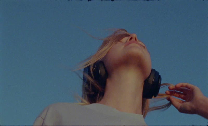 A young girls with headphones on stands out in the wind listening to music and moving her head around