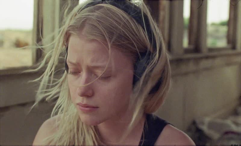 A womans hair is blowing in the wind in the run down home