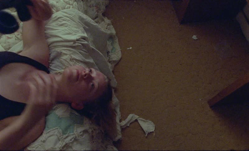 A young woman removing her headphones while lying on a bed