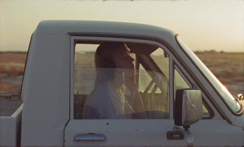 A woman sitting in a truck with headphones listening to music