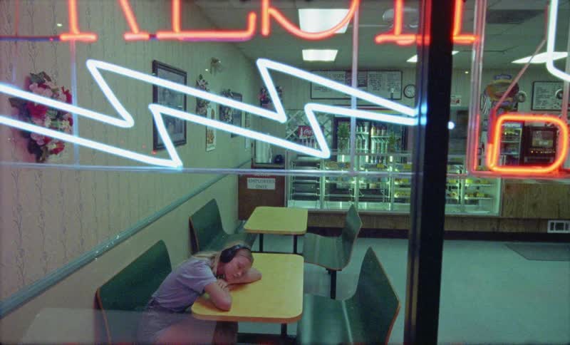 A young woman listening to headphones in an empty diner