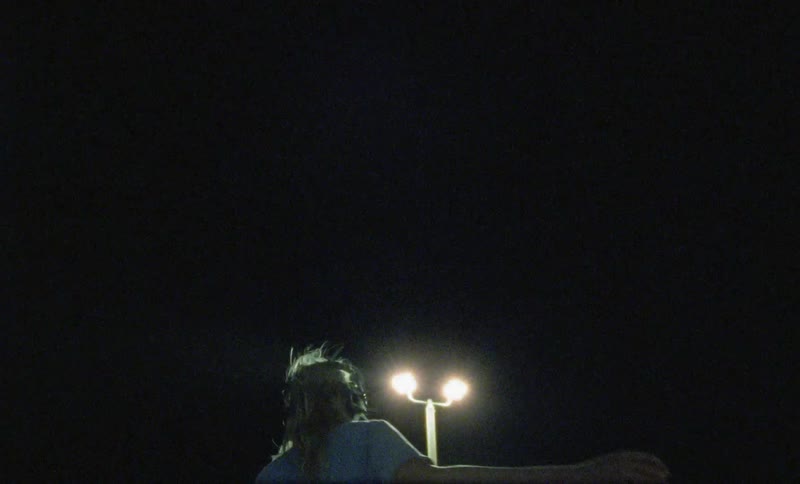 A young white woman wearing headphones dances outdoors at night