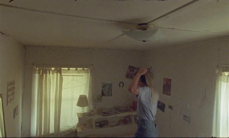 Blonde girl wearing headphones jumps on the bed in a room during daylight