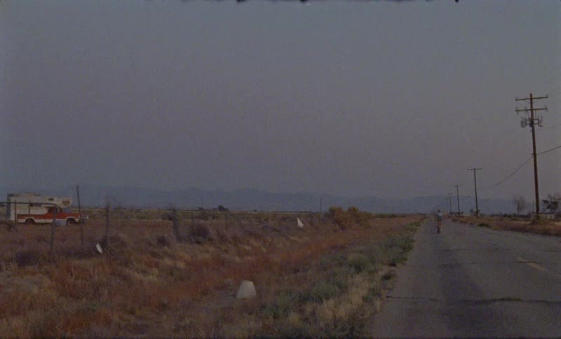 A person rides a bike down the road in the desert