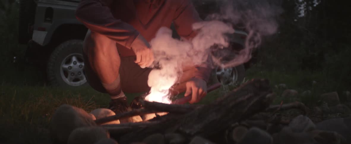 A man ignites a flare to start a campfire