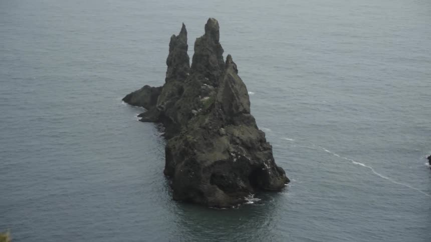 A bird flies on the shoreline amongst rock formations