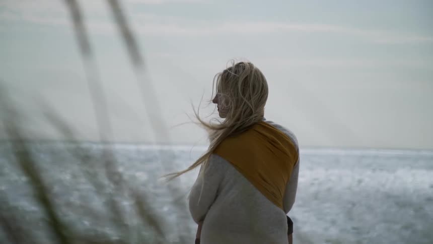 A woman overlooks the ocean on a windy day
