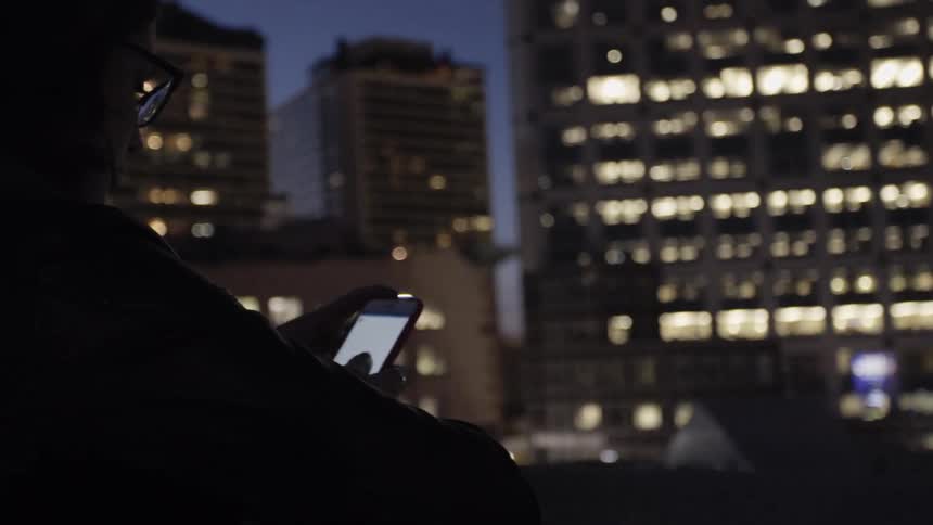 Woman checks phone while standing on balcony