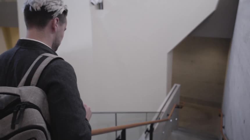 A man wearing a backpack walks down outside stairs