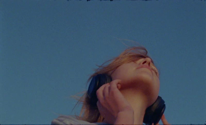 A woman with headphones listening to music and dancing in the wind