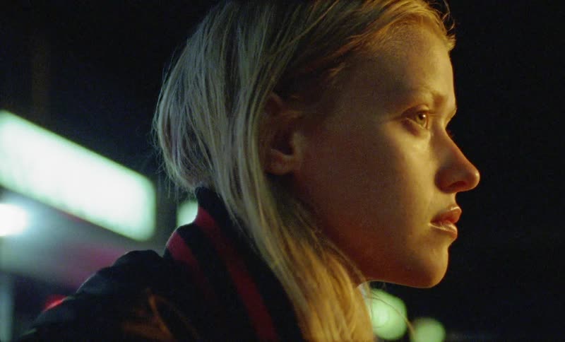 A woman is looking around outside at night