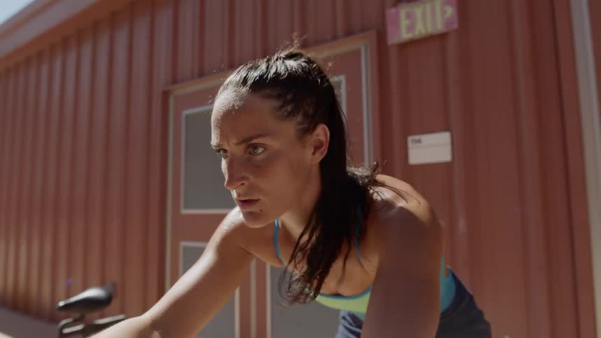 A woman is exercising outside on a stationary bike