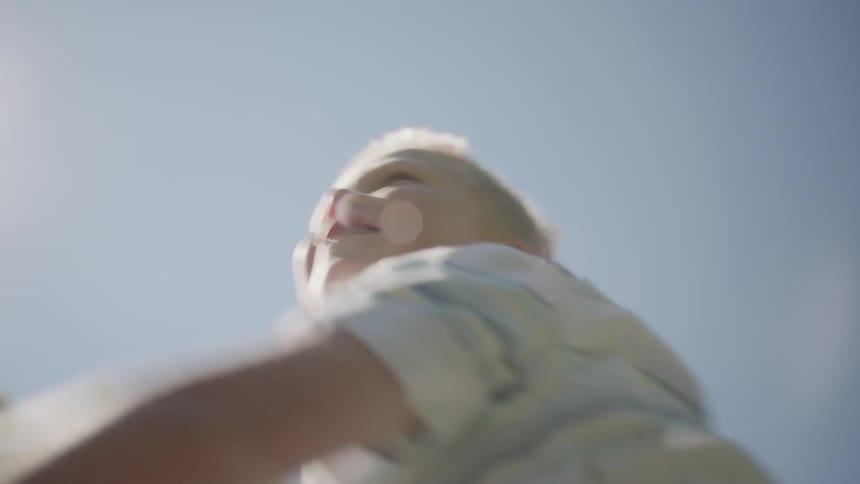 Young boy smiles while throwing a red and yellow basketball as far as he can outside on a sunny day