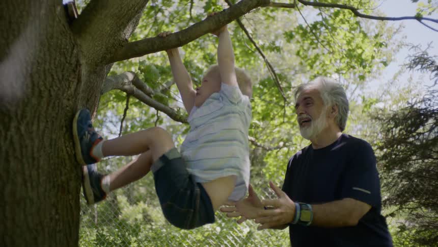 A grandfather playing with his grandson at the tree