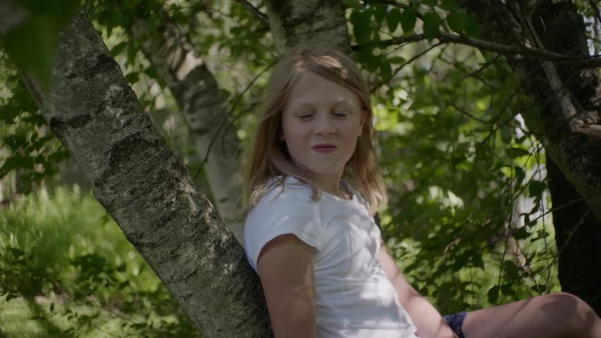 A young girls sits in a tree
