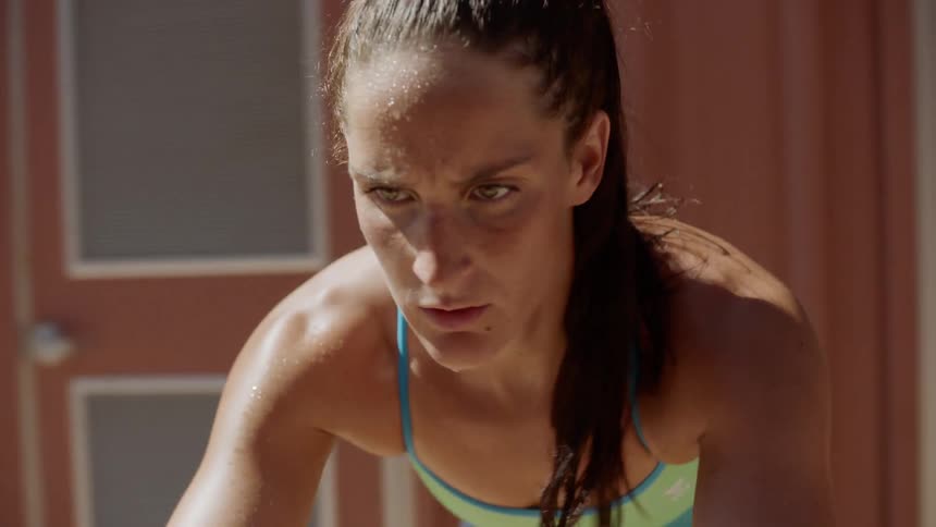 A female is sweating while riding a stationary bike in the sun outside