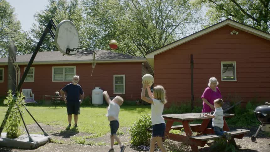 Children shoot basketballs into the hoop in the yard