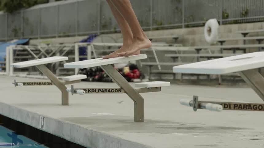 A female steps on to a starting block at a pool
