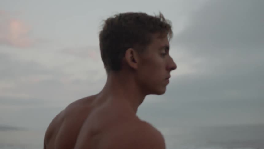 A shirtless man contemplating at the beach