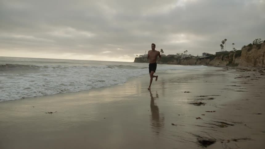 A white man jogs across a beach